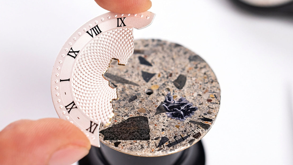 main d un horloger tenant le cadran d une montre berlin en cours d assemblage