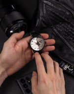 montre mur de berlin portee a la main par un homme avec appareil photo et veste en cuir